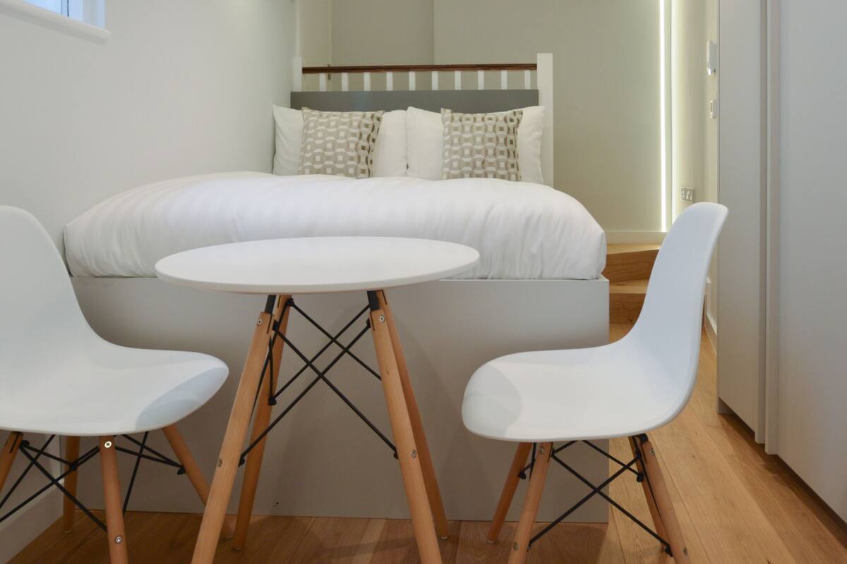 A modern bedroom with a bed, a round table, and two chairs.