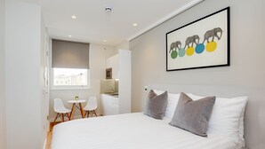 A bedroom with a large bed, a small desk, and a chair. - StayPrime Kensington Serviced Apartments (London)