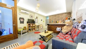 A cozy living room with a sofa, a coffee table, and a bookshelf. - Cat Mia Hostel (Hualien City)