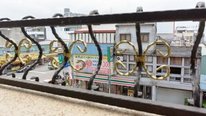 A view through a metal fence with buildings and a street in the background. - Cat Mia Hostel (Hualien City)