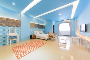Quarto moderno com cama, uma cadeira, escrivaninha e televisão.