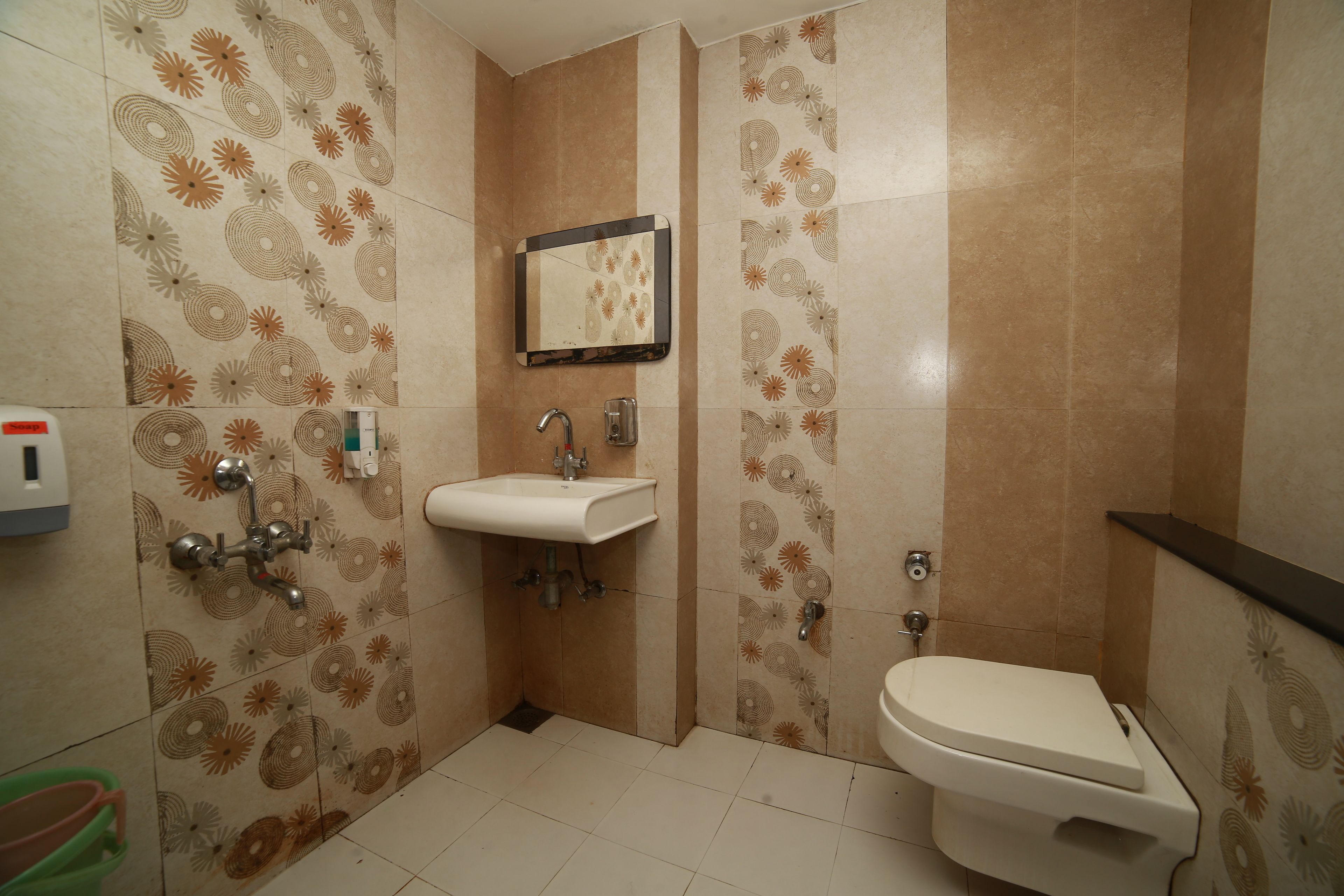 Un baño con baldosas estampadas, un lavamanos, un espejo, un inodoro y una ducha.