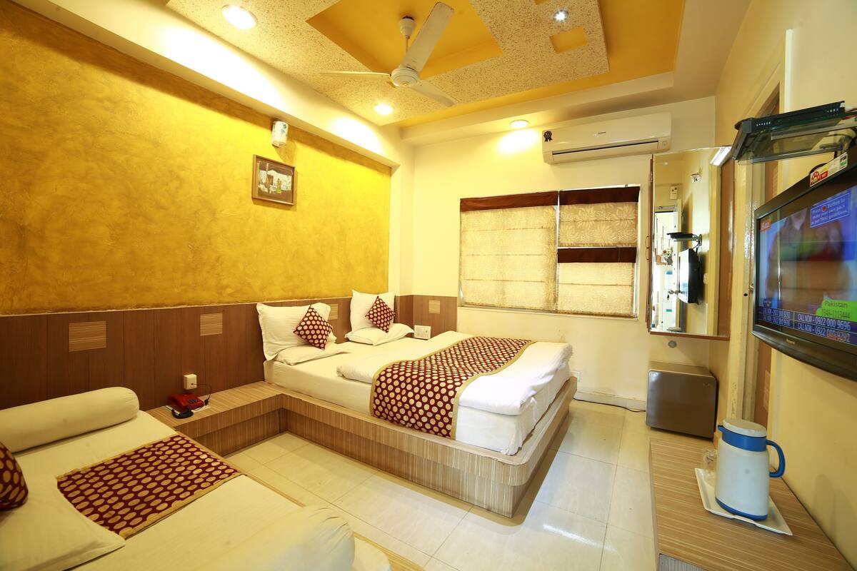A hotel room with a bed, a sofa, a TV, and a coffee maker.