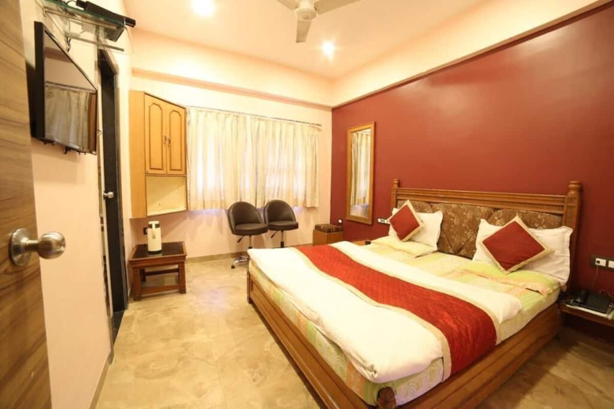 A bedroom with a bed, a nightstand, a chair, a window with curtains, and a ceiling fan.