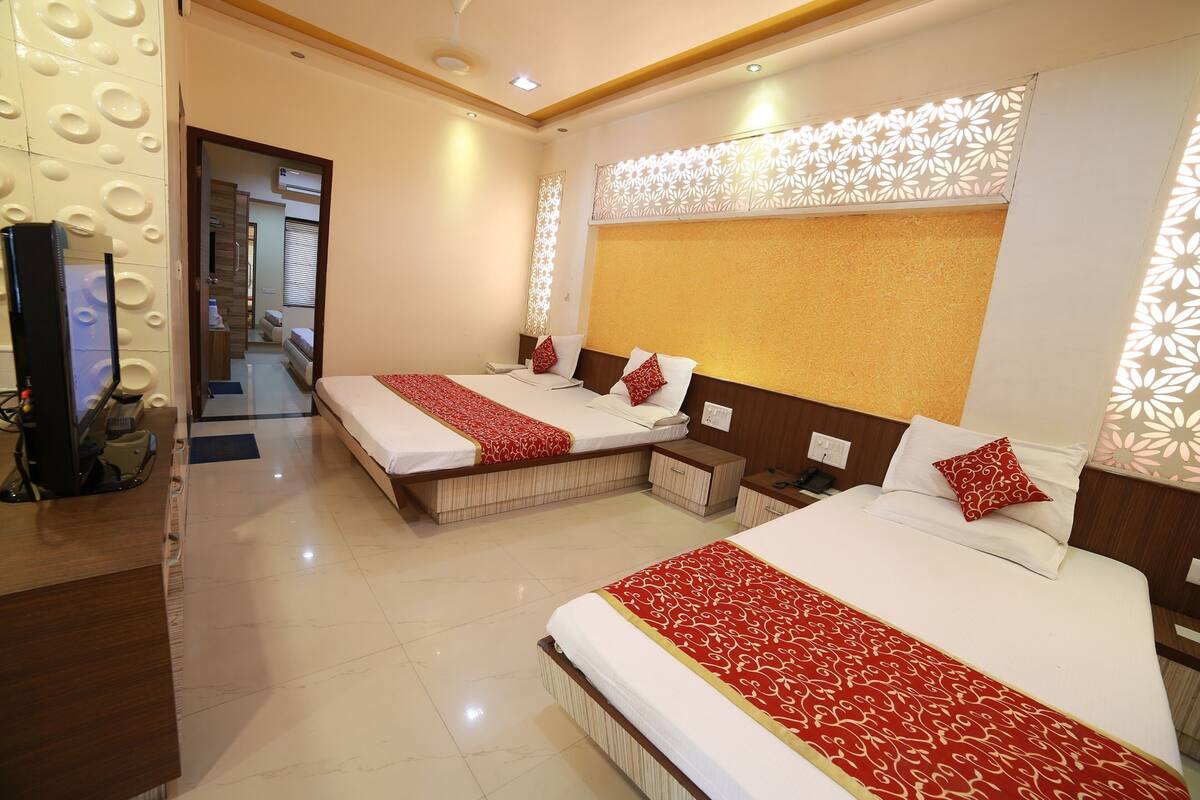 A hotel room with two beds, a wooden desk, and a television.