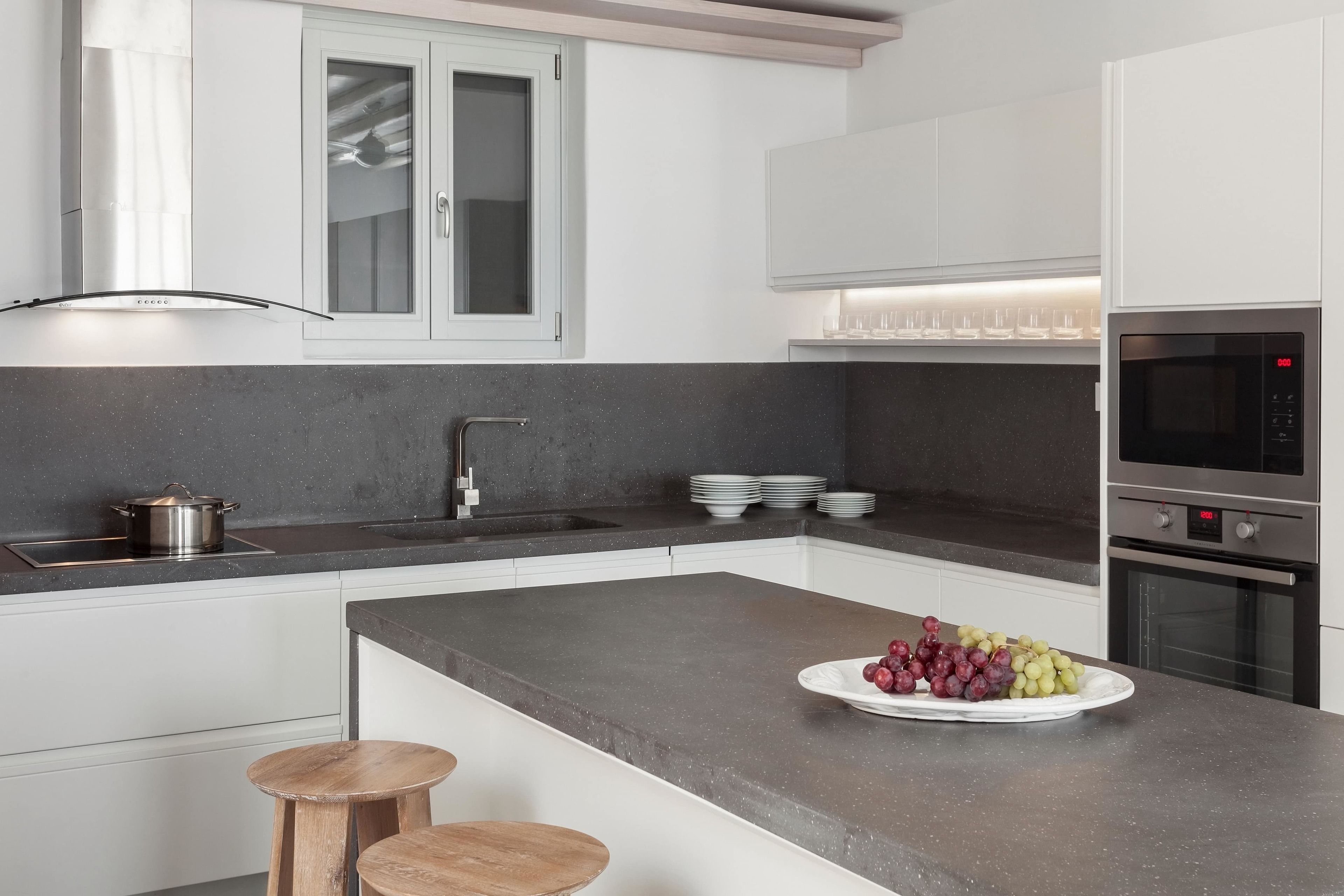 A modern kitchen with white cabinetry, a granite countertop, a built-in oven, and a sink.