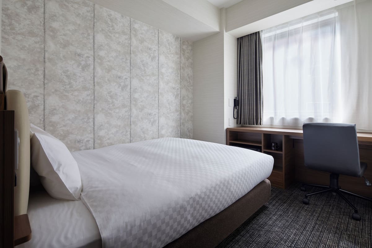 Una habitación de hotel con una cama, un escritorio y una silla.