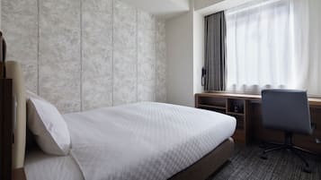 A hotel room with a bed, a desk, and a chair.