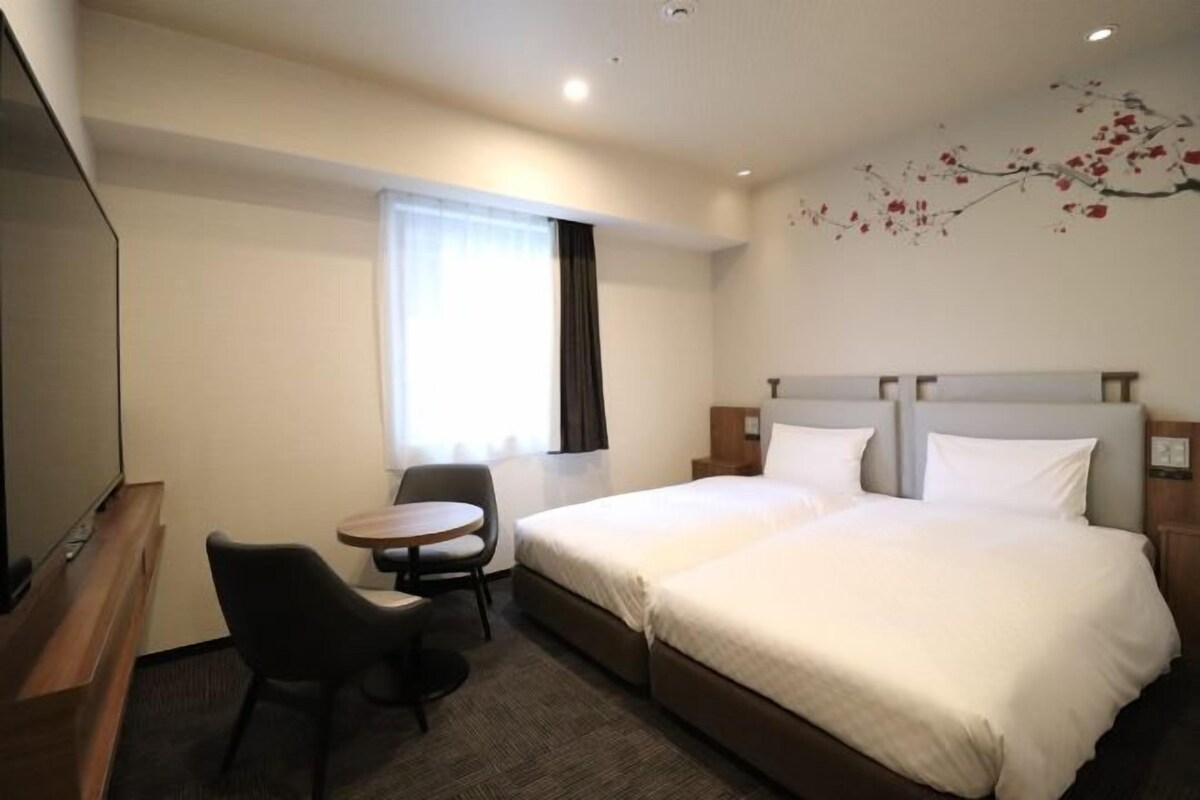 Ein Hotelzimmer mit Bett, Schreibtisch, Stuhl und Fernseher.