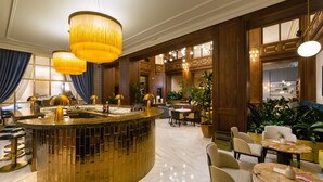 Un hall d’entrée luxueux doté d’un bar central, de différents espaces aménagés pour s’asseoir et d’un éclairage décoratif.