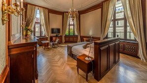 Une chambre d’hôtel avec un grand lit, un bureau, une chaise, une télévision et un lustre.