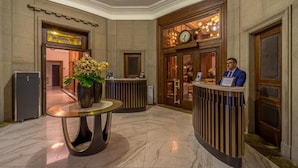 Un hall d’entrée avec un comptoir de réception, une horloge et un vase rempli de fleurs.