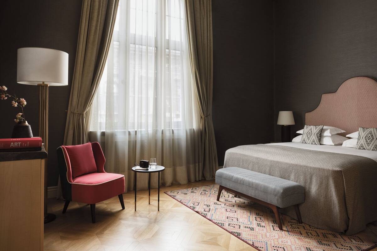 Ein Hotelzimmer mit einem Bett, einem Sessel, einem kleinen Tisch und einer Lampe.