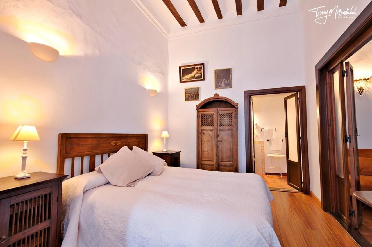 A bedroom with a wooden bed, bedside lamps, a wardrobe, and a mirror.