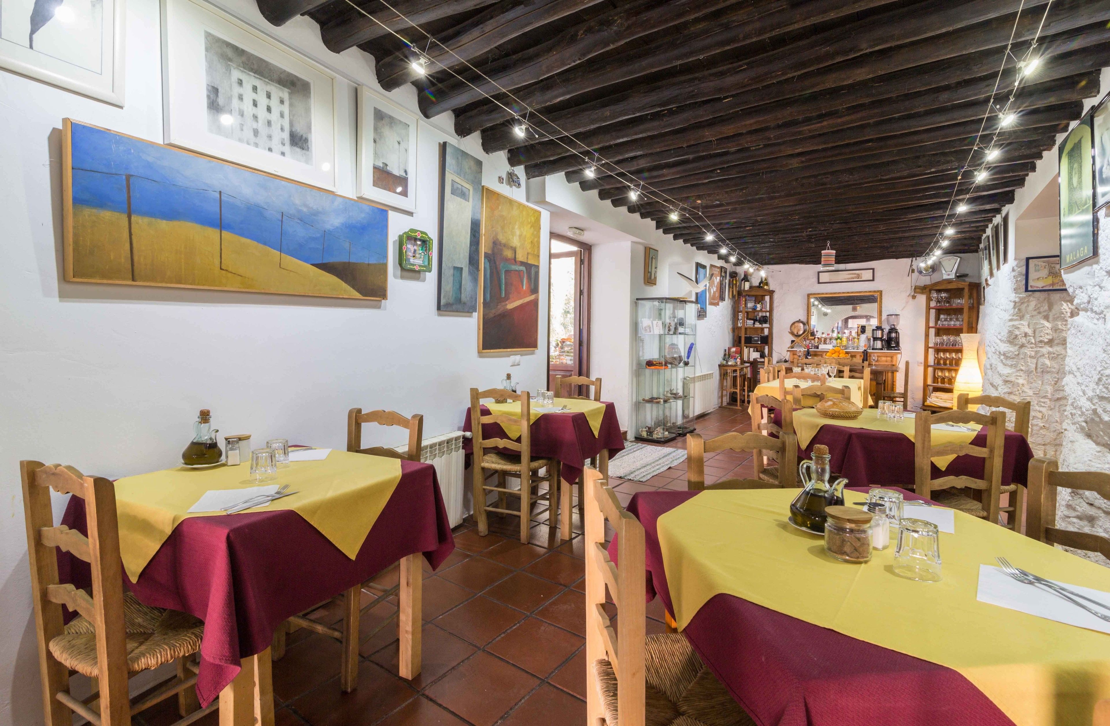 Un restaurante con mesas dispuestas para comer, sillas de madera y suelo de baldosas.