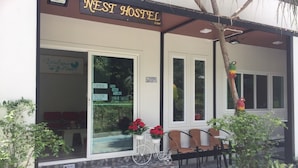 A hostel with a sign reading "NEST HOSTEL" and amenities listed as "OPEN, FREE WiFi, Coffee, SLIDE." - Nest  Hostel Lipe (Koh Lipe)