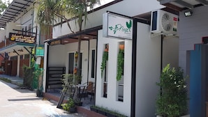 A hostel with a signboard, outdoor seating, and a fan. - Nest  Hostel Lipe (Koh Lipe)