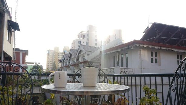 Una terraza en la azotea con una mesa redonda de metal, dos sillas y plantas en macetas.