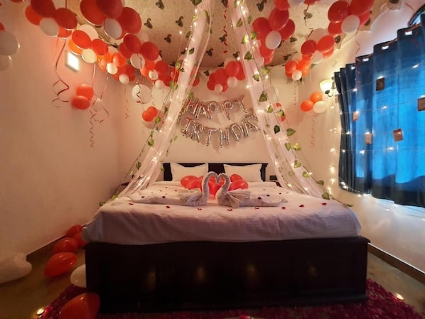Una cama con dosel, rodeada de globos y luces colgantes.