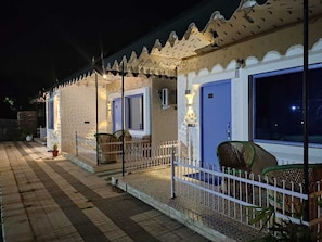 A row of small, single-story buildings with individual doors, each with a small porch and a white railing.