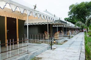 A row of traditional-style buildings with a uniform facade, a gated entrance, and a paved walkway. - The Timber Garden Adventure Club (Jaipur)