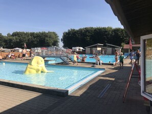 Uma área de piscina com várias piscinas, um posto de salva-vidas e um brinquedo flutuante amarelo.