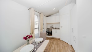 Una cocina moderna con armarios blancos, encimera de madera y un comedor con mesa dispuesta para dos.