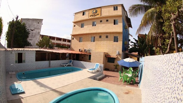 A hotel with a swimming pool, outdoor seating, and a building with multiple floors. - Pousada Mar do Sonho (Ipojuca)