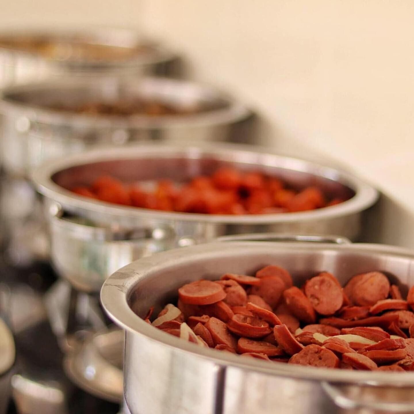 Un bufé con distintos alimentos en recipientes metálicos.