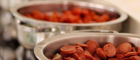 Un bufé con distintos alimentos en recipientes metálicos.