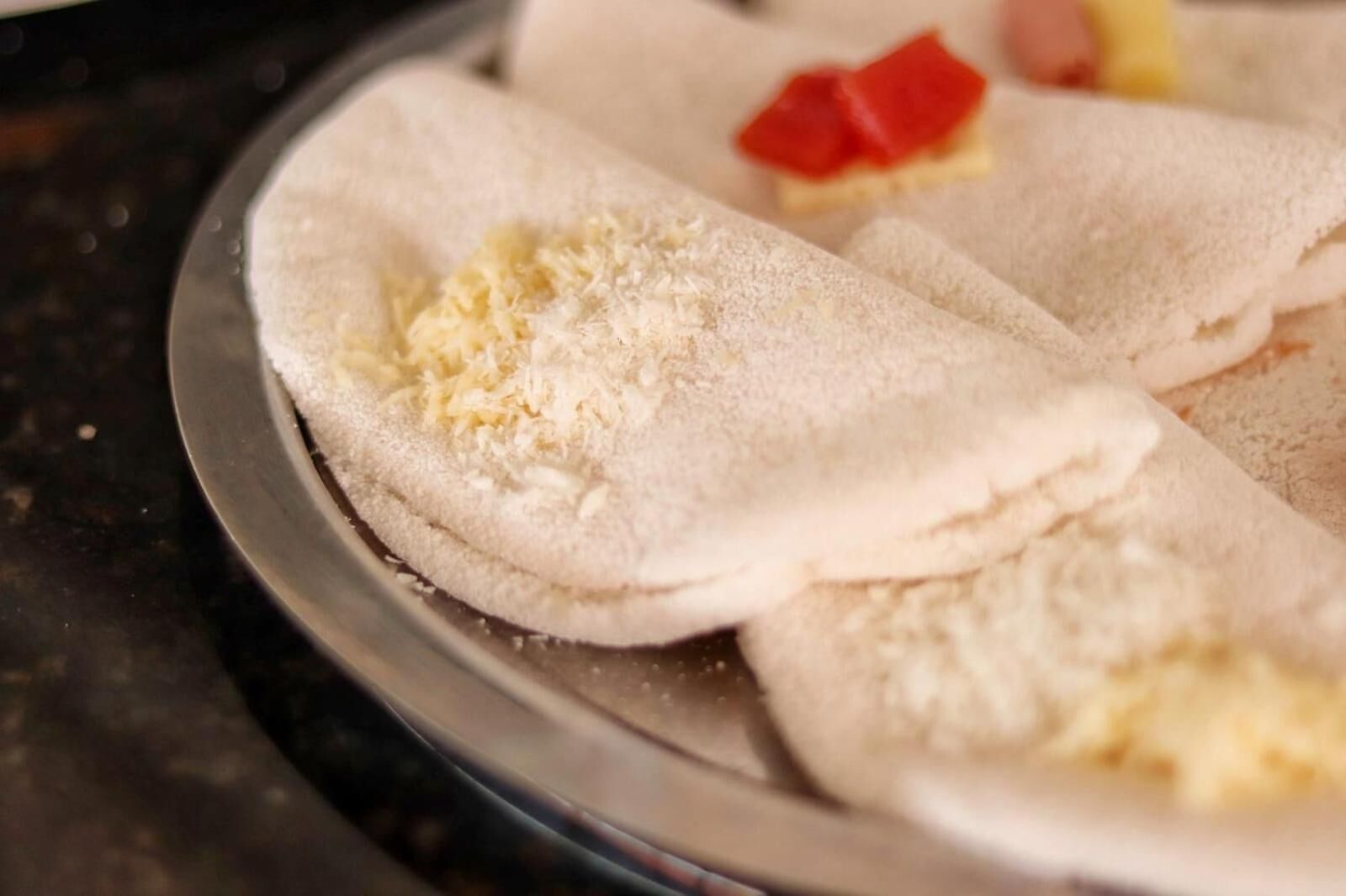Una bandeja con varias piezas de pan plano, algunas cubiertas con queso.