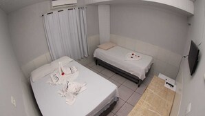 A hotel room with two beds, a small table, and a TV mounted on the wall. - Pousada Mar do Sonho (Ipojuca)
