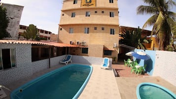 Una piscina al aire libre, sillones reclinables de piscina