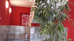 A reception area with a staircase, a reception desk, and a large potted plant. - Ricks City Hotel 2 (Trier)