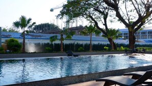 A swimming pool with lounge chairs and palm trees. - Sann Hotel (Chiang Rai)