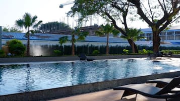 Una piscina al aire libre, sombrillas, sillones reclinables de piscina