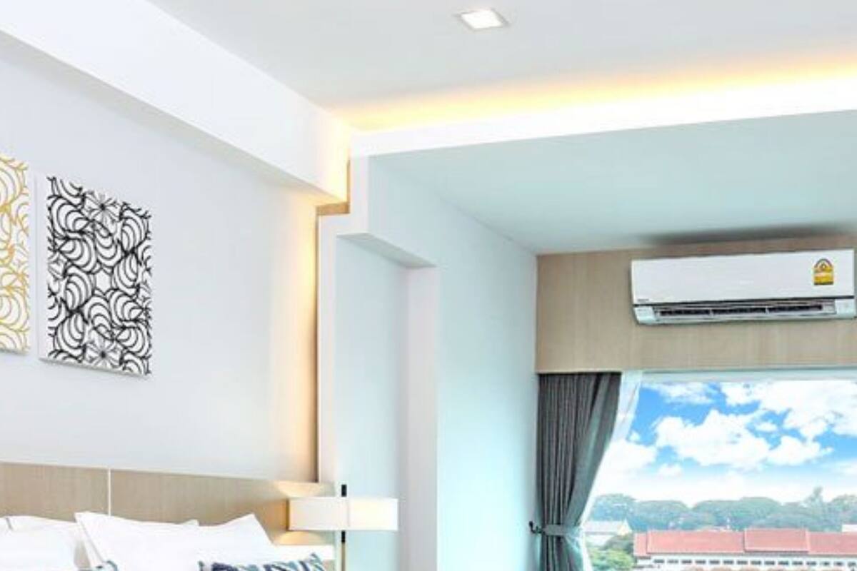 Una habitación de hotel moderna con una cama grande, vistas de la ciudad y un equipo de aire acondicionado.