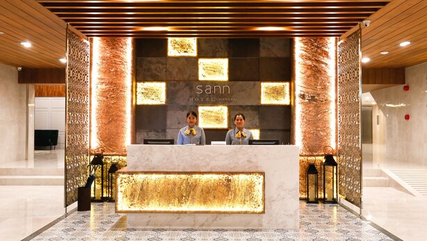 A hotel reception desk with a modern design, featuring a marble counter and decorative lighting. - Sann Hotel (Chiang Rai)