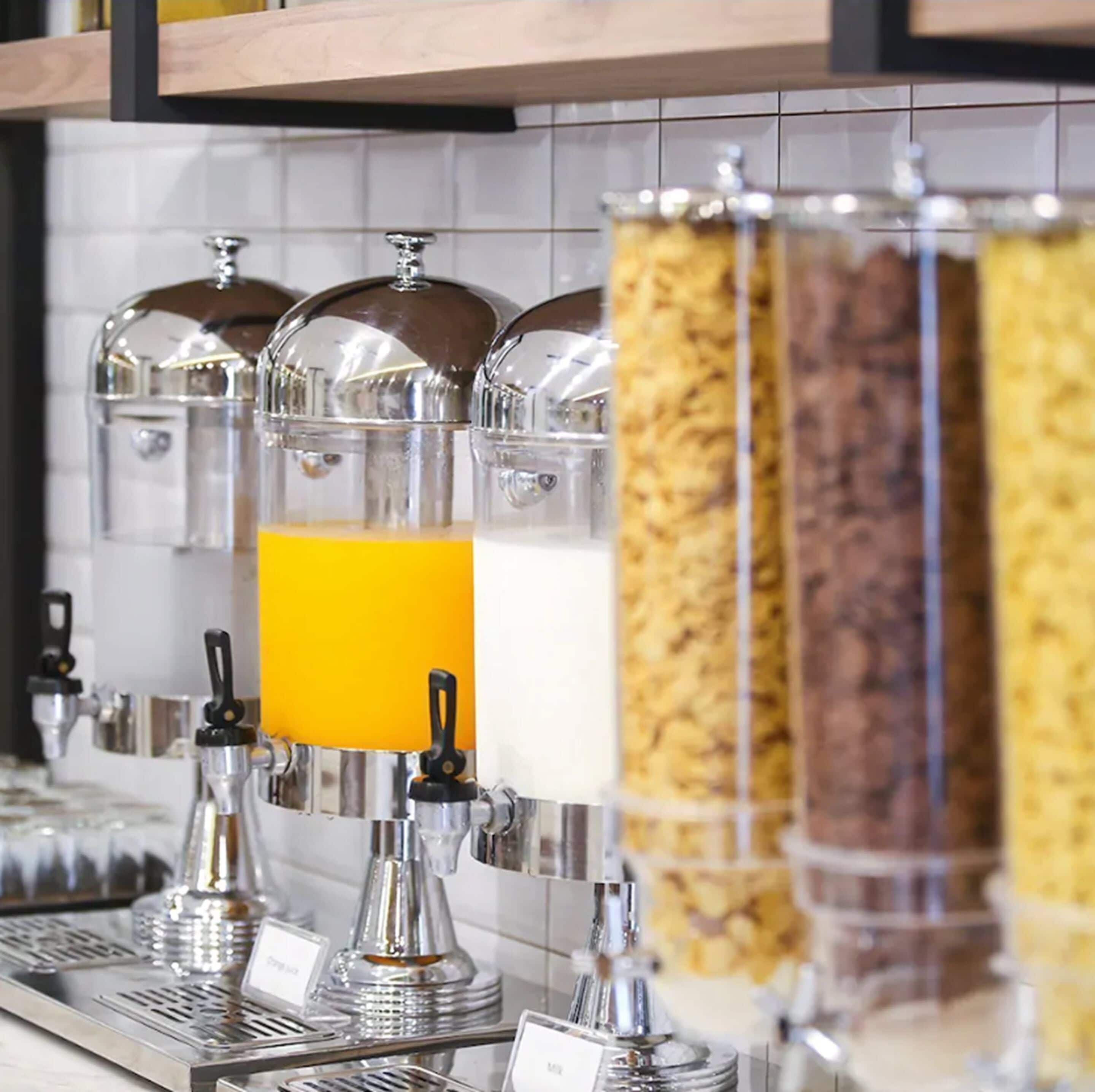 A breakfast bar with dispensers for orange juice, milk, and cereal.