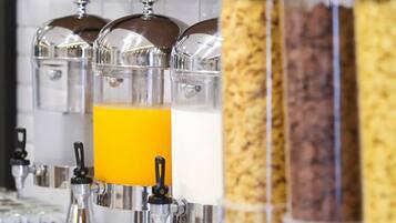 Una barra de desayuno con dispensadores para jugo de naranja, leche y cereal.