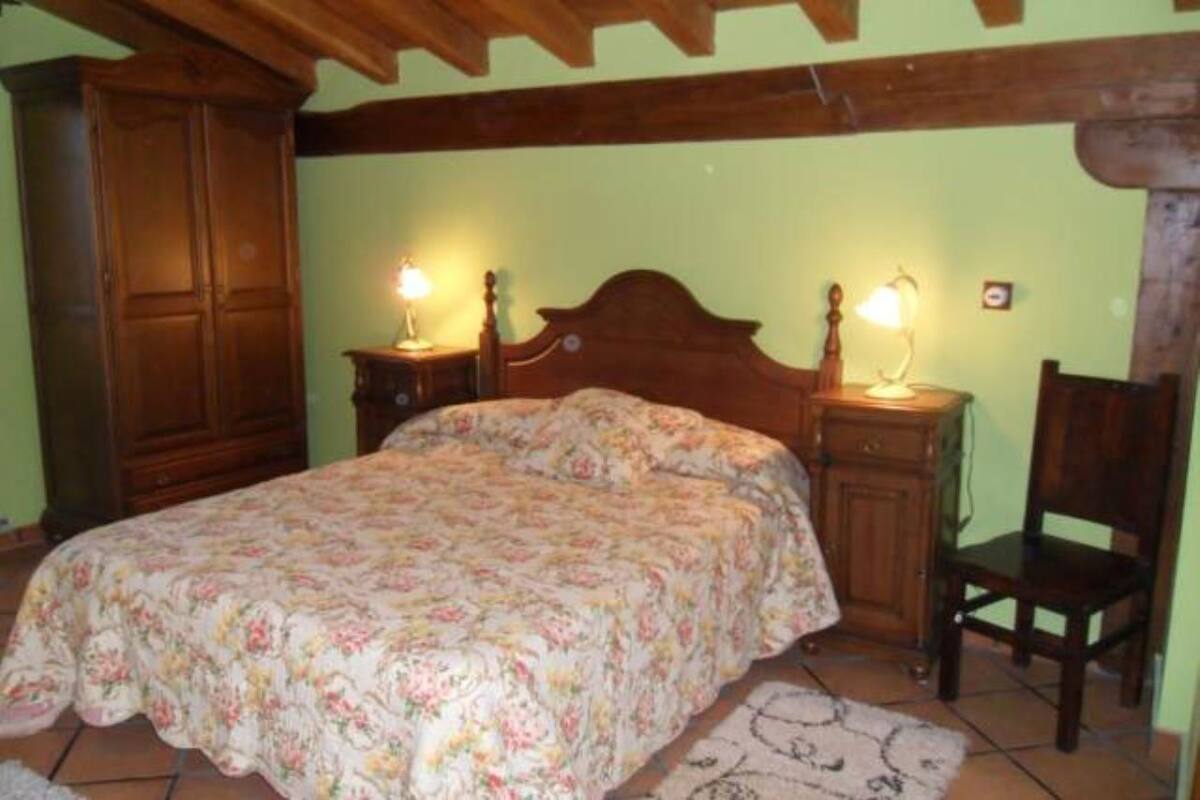 A bedroom with a floral bedspread, wooden headboard, two bedside tables with lamps, a wooden wardrobe, and a chair.