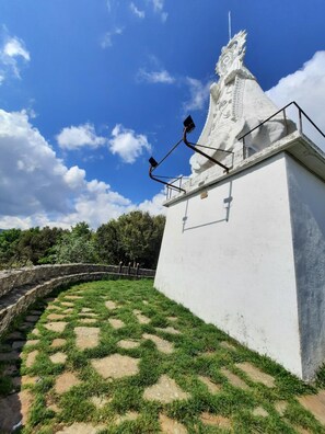 A white building with a decorative roof and a stone bridge in the background. - Casa Rural Aingeru (Valle de Carranza)