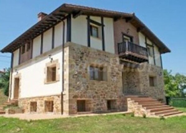 A two-story stone house with a balcony on the upper floor. - Casa Rural Aingeru (Valle de Carranza)