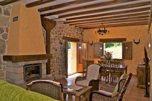 Un interior acogedor con chimenea de piedra, vigas de madera en el techo, muebles de mimbre y un comedor con vistas.