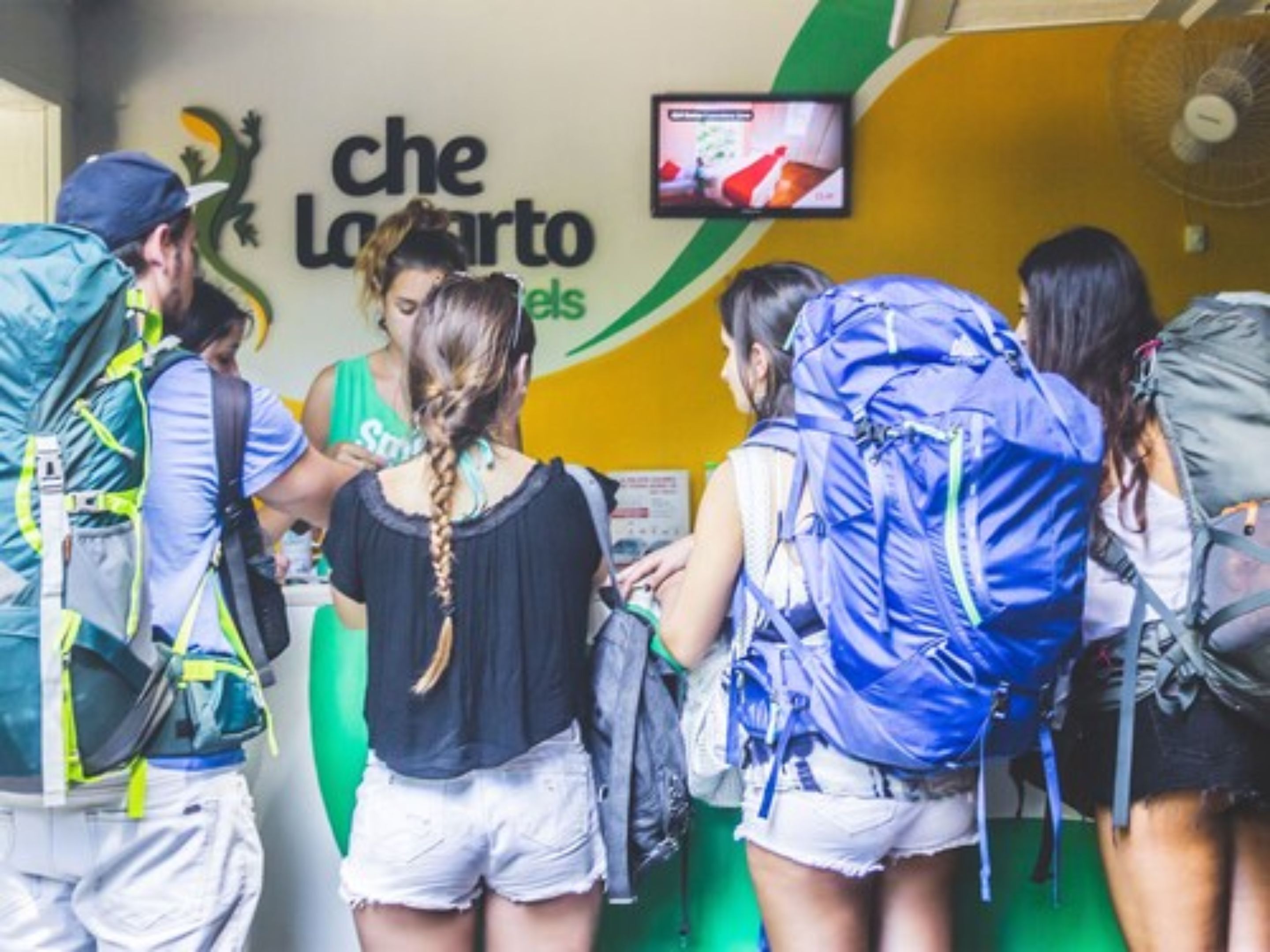 A group of people with backpacks at a counter, possibly a hostel or hostel-like accommodation.