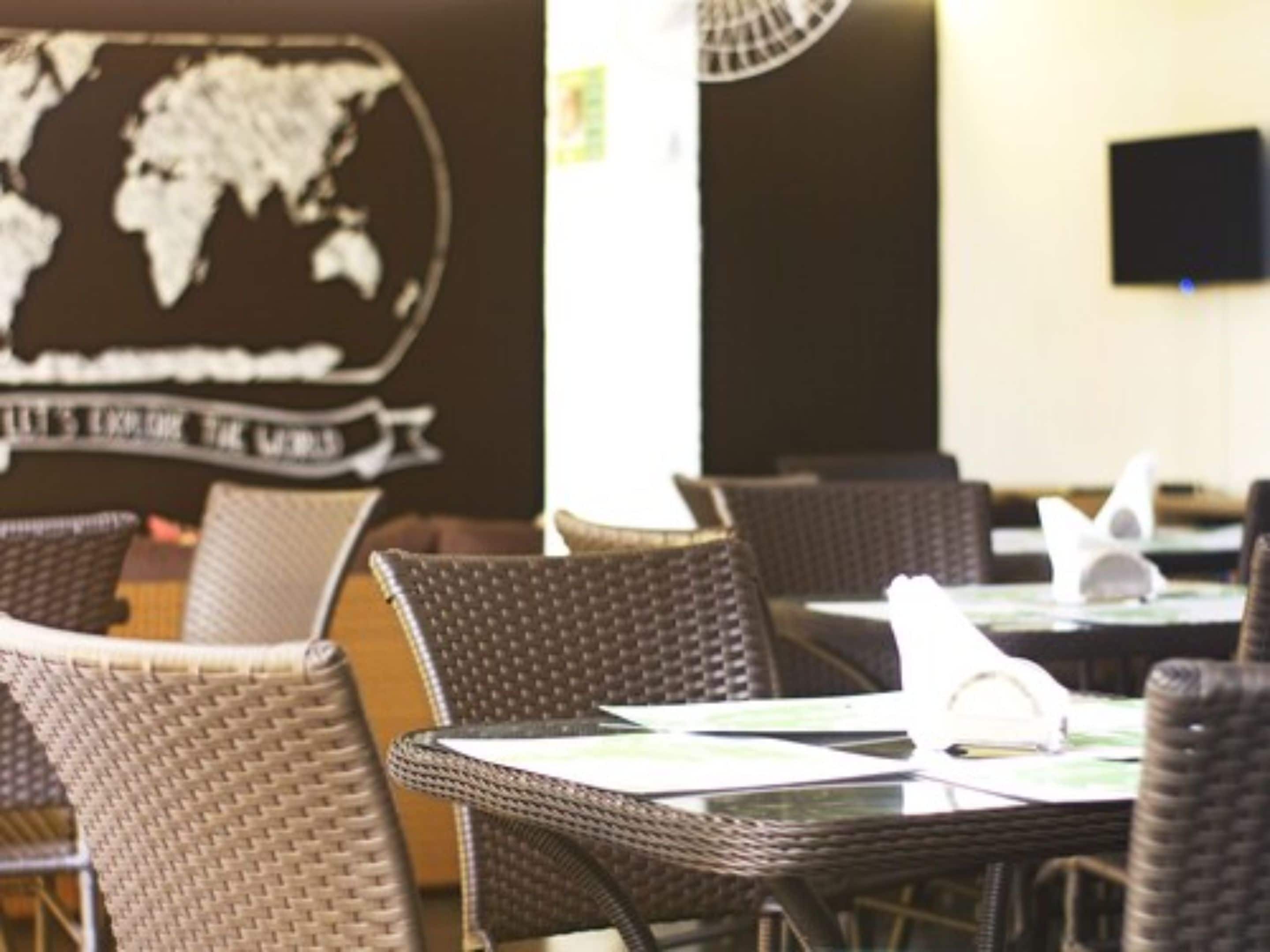 A restaurant interior with wicker furniture and a world map on the wall.
