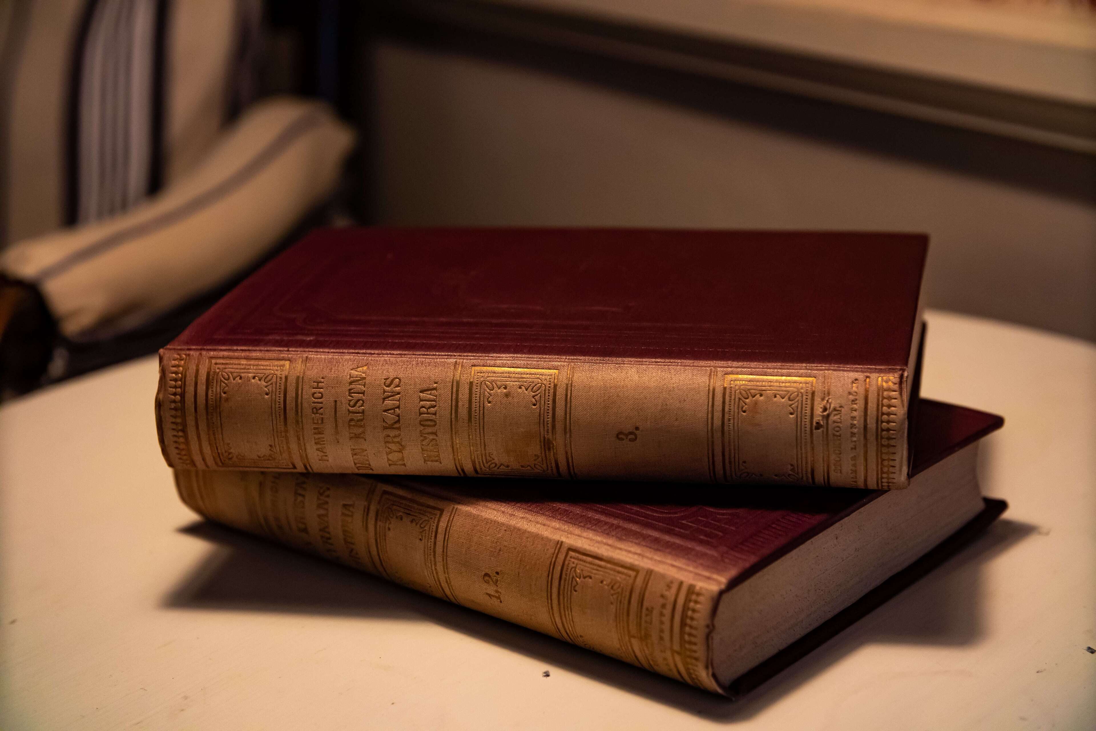 Zwei alte Bücher auf einer weißen Oberfläche gestapelt.