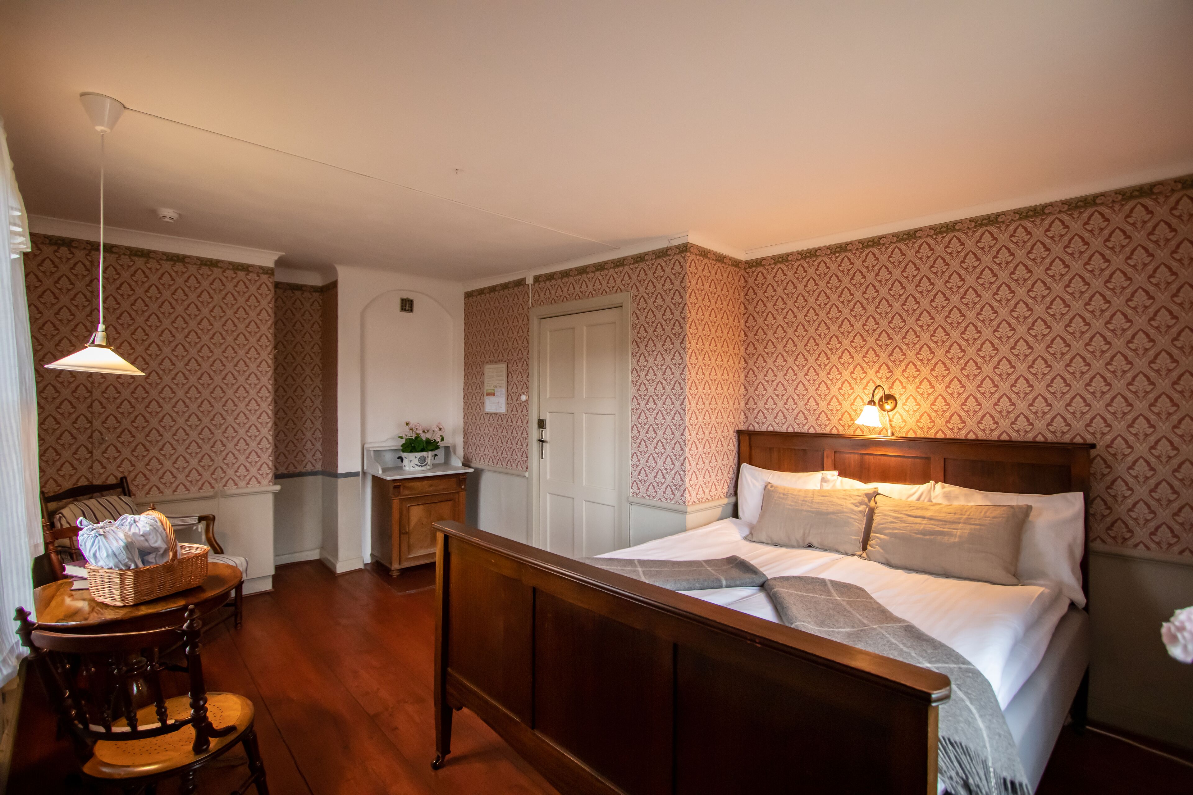 A neatly arranged bedroom with a wooden bed, a bedside table, and a chair.