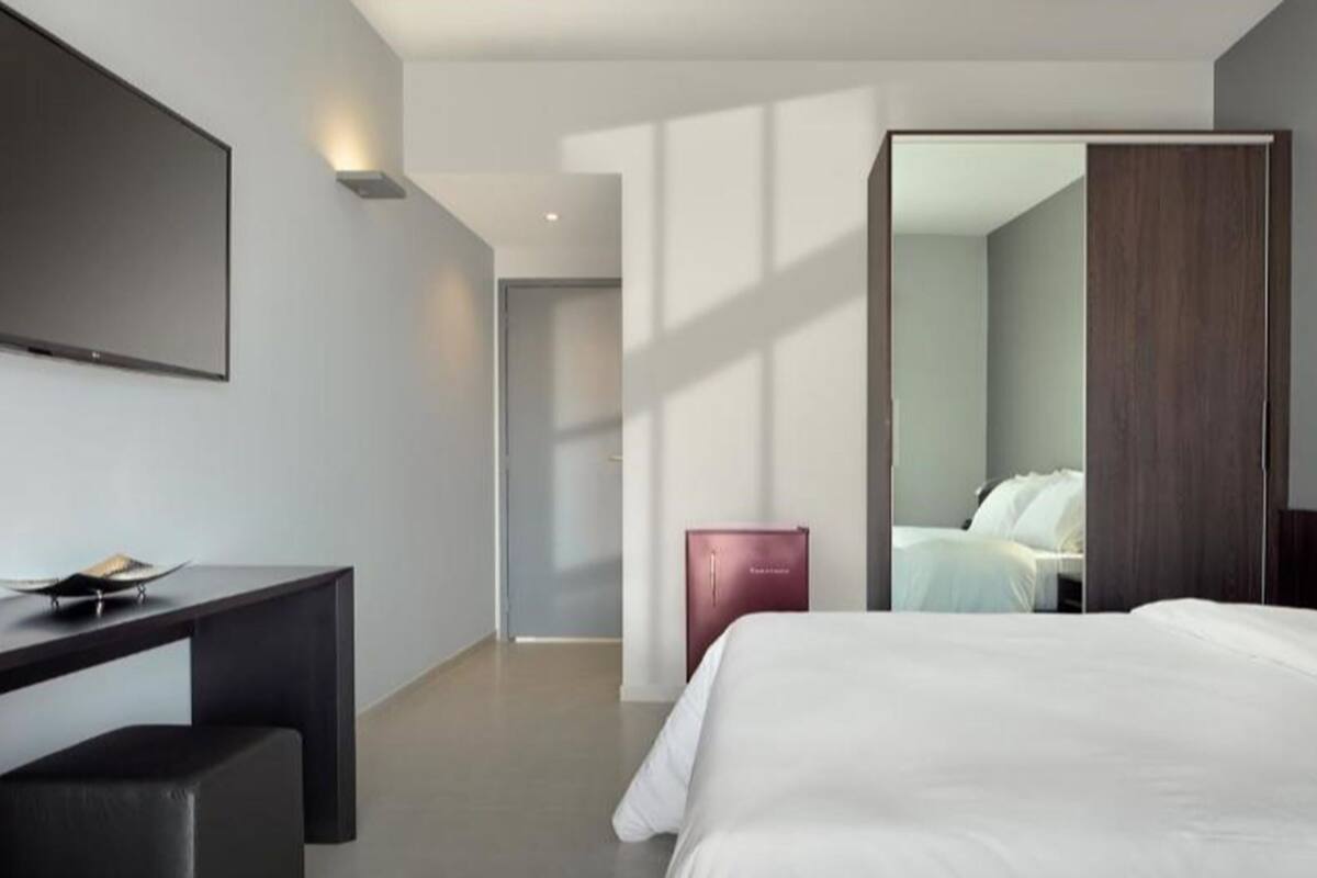 Quarto de hotel moderno com uma cama grande, uma escrivaninha e um guarda-roupa.