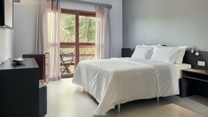 A modern bedroom with a large bed, a desk, and a view of palm trees through a window. - Rox by Essenza Hotel (Jijoca de Jericoacoara)